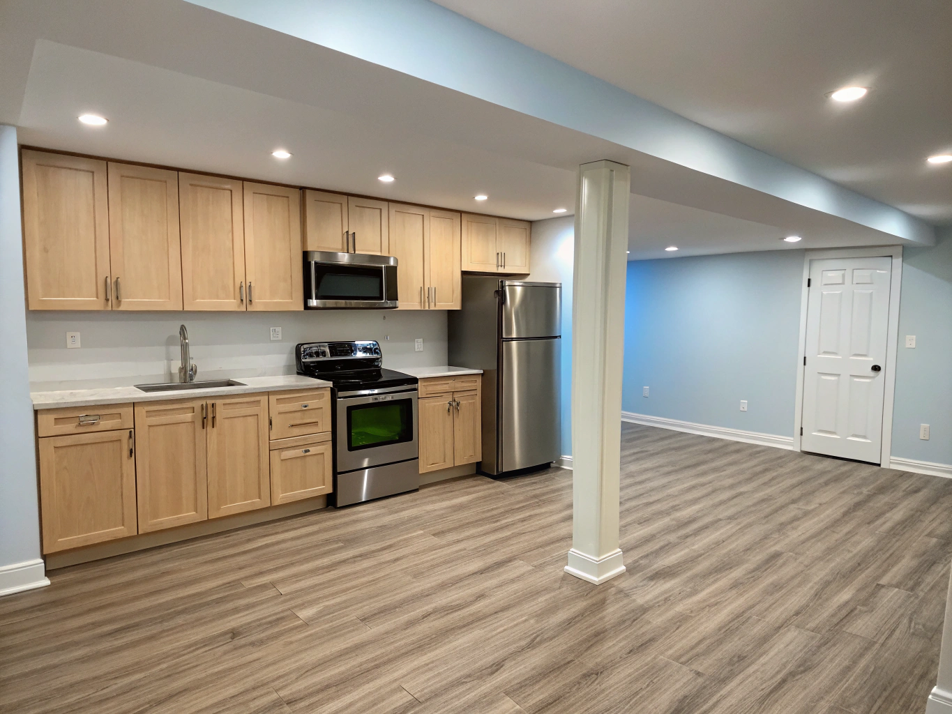 Bright walkout basement guest suite featuring a sleek modern kitchenette and wood flooring