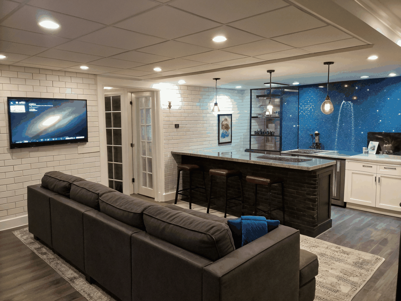 Finished terrace-level basement remodel featuring custom hospitality wet bar, quartz countertops, modern recessed lighting, and entertainment lounge area