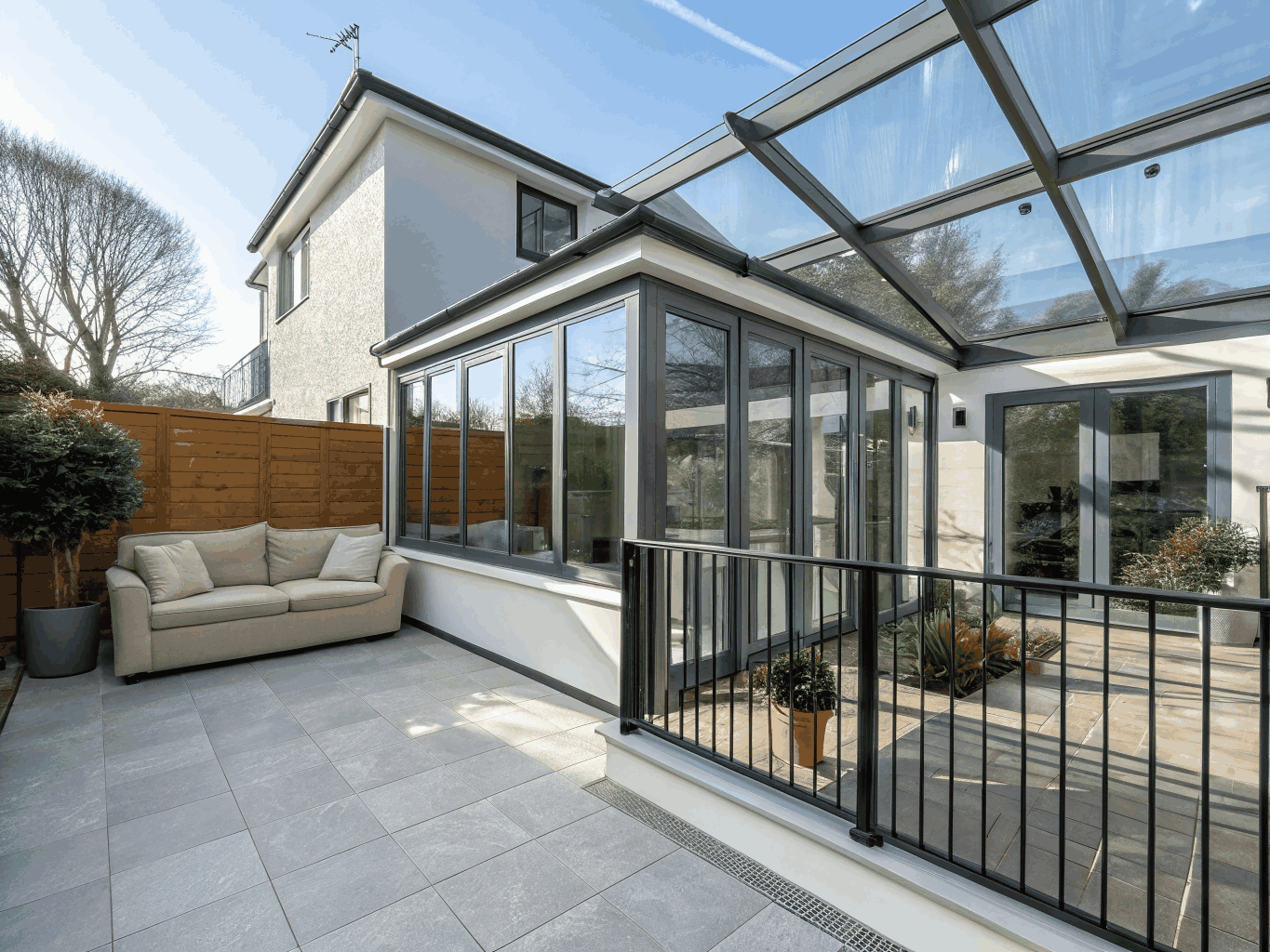 Light-filled sunroom addition with exposed timber ceiling beams, expansive picture windows, and heated flagstone floors