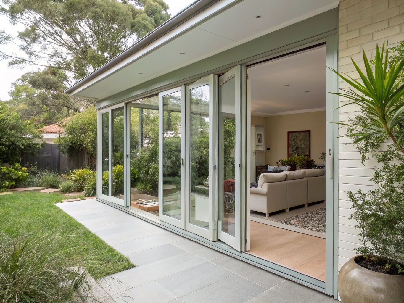 Transitional indoor-outdoor family room renovation opening onto a covered bluestone patio with glass bi-fold doors in Vinings Crest